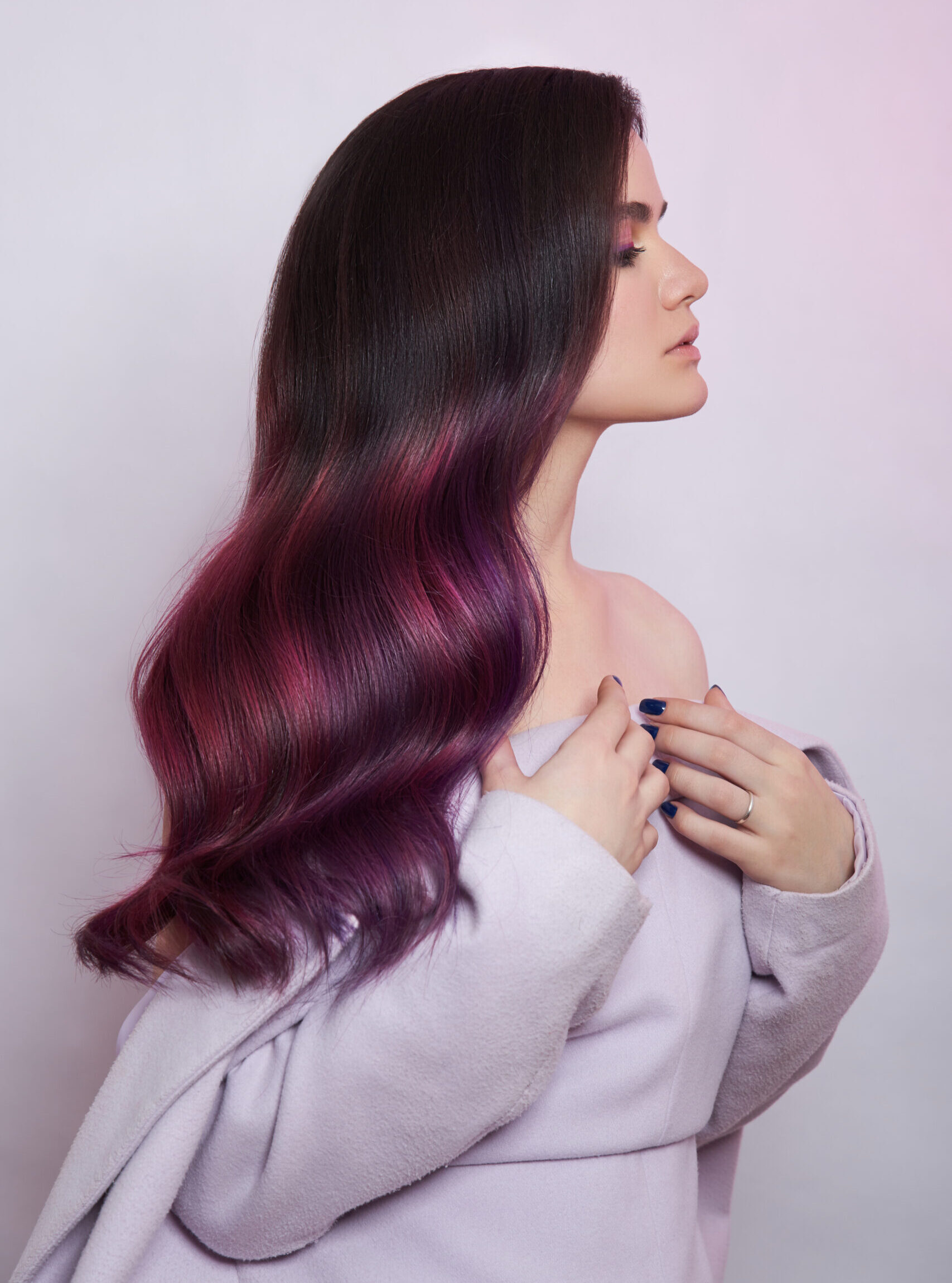 Portrait of a woman with bright colored flying hair, all shades of purple. Shiny Healthy colored Hair coloring, beautiful lips and makeup. Sexy girl with long hair styling